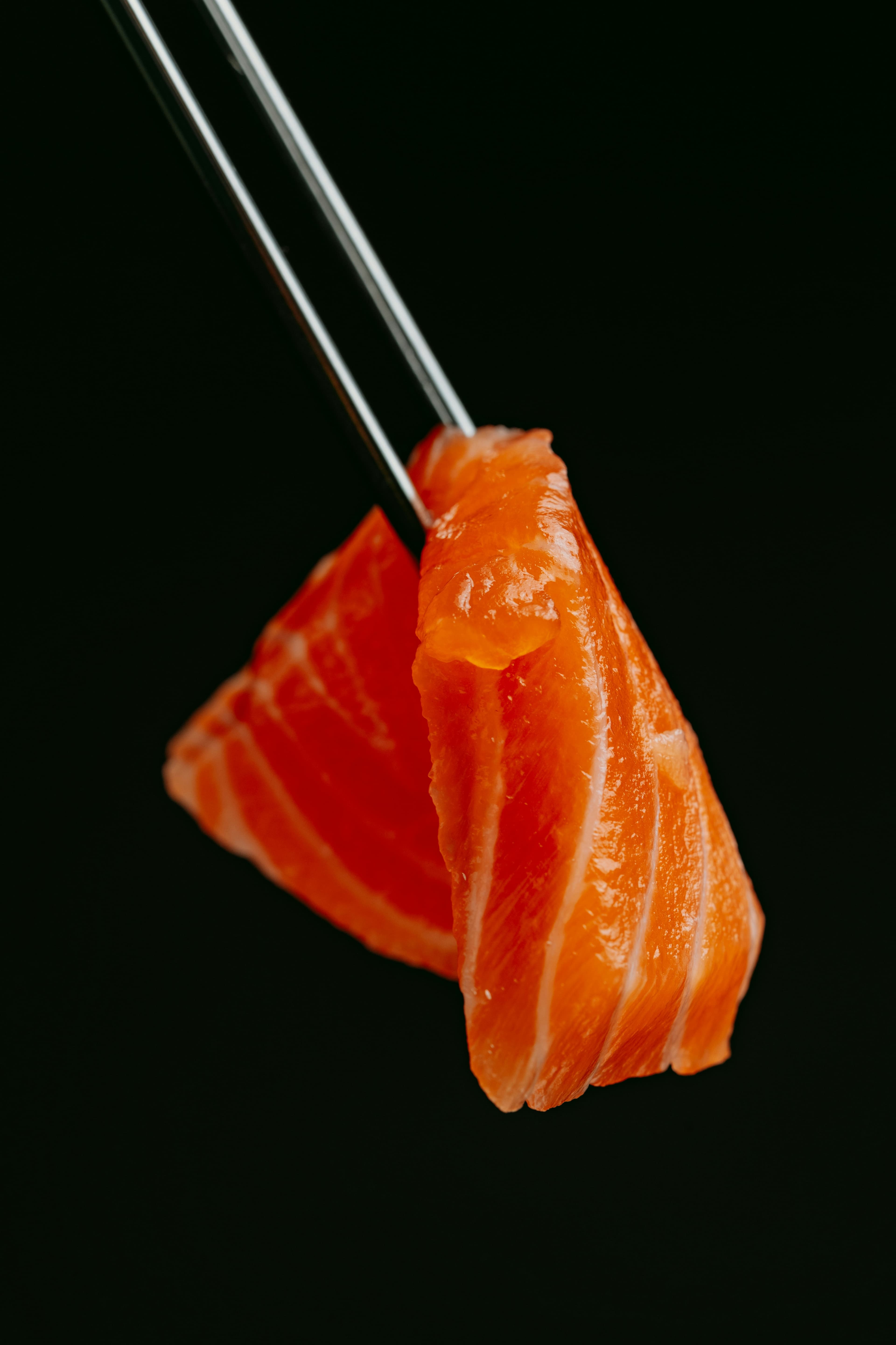Fresh salmon sashimi held with chopsticks