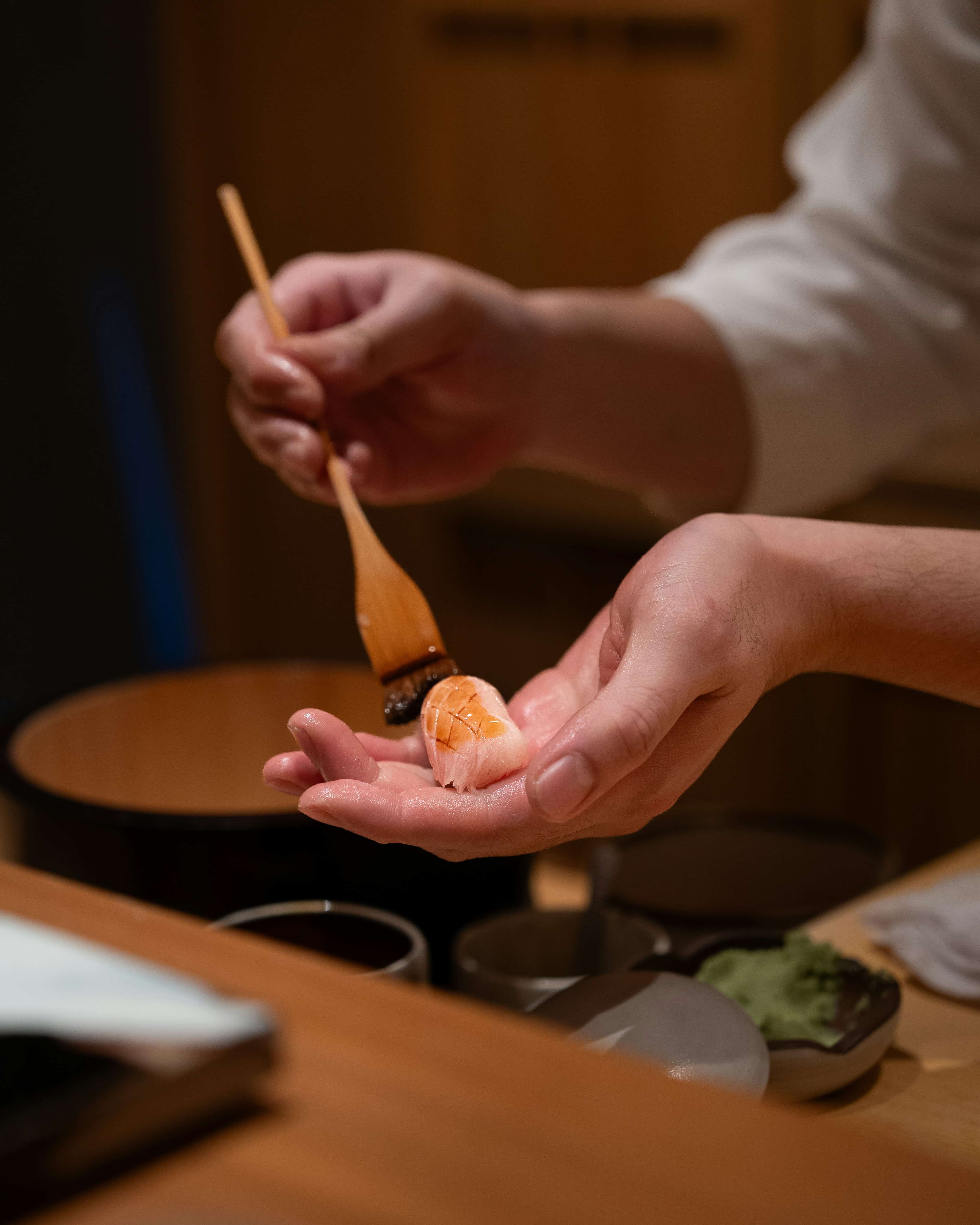 Chef dressing nigiri with glaze