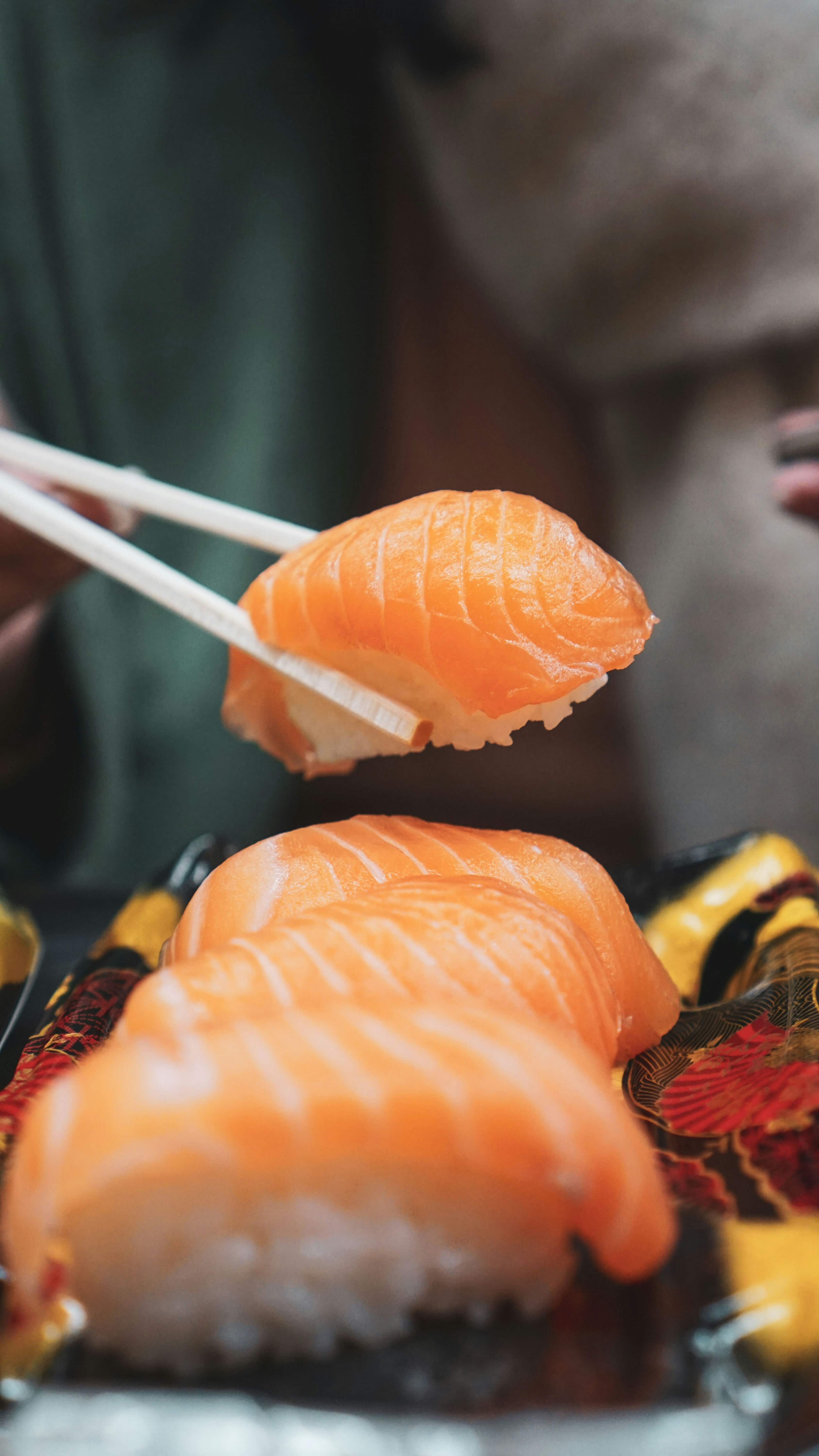 Salmon nigiri lifted with chopsticks